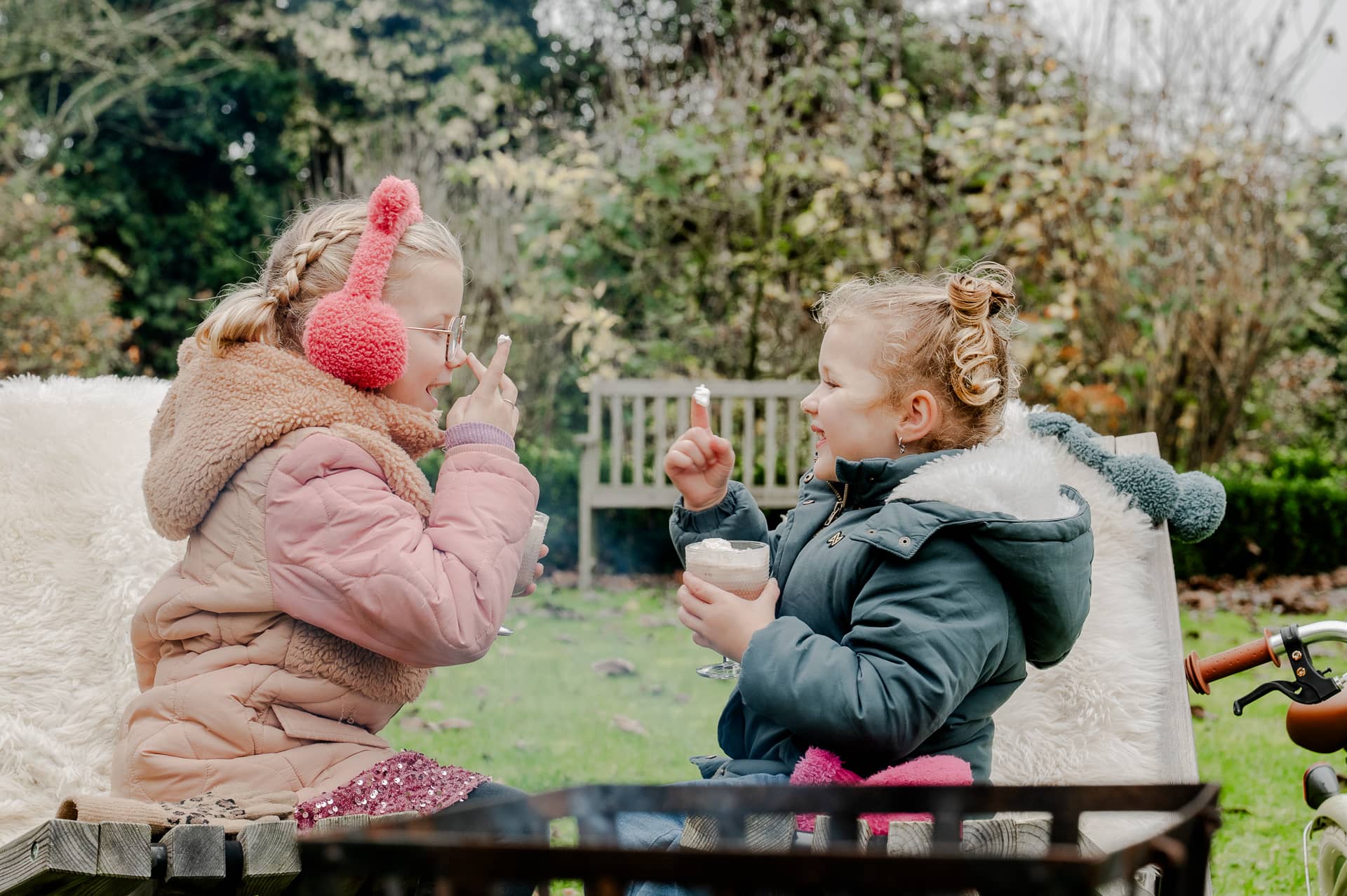 Twee kinderen met warme chocolademelk in de tuin
