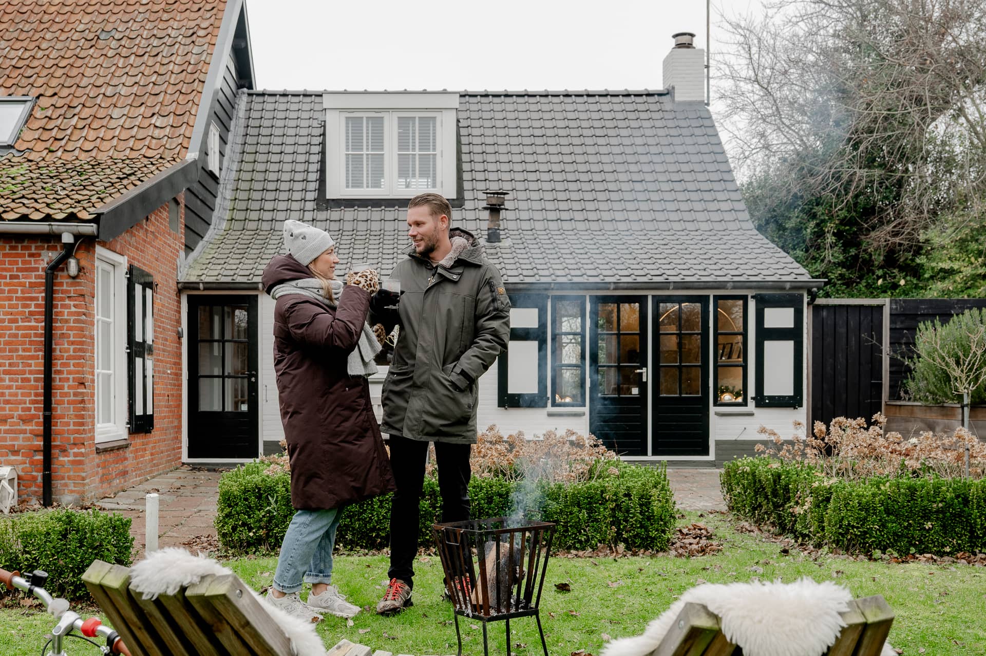 Stel bij een vuurkorf in de tuin van een vakantiehuis in de winter